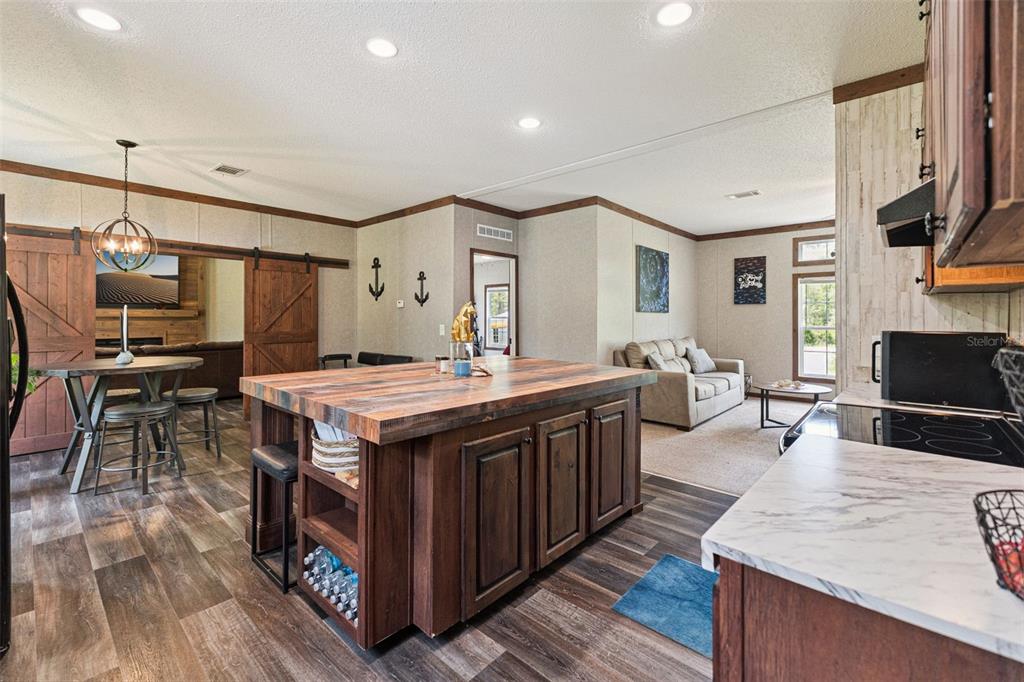 A tan manufactured home sits behind a gravel driveway with two storage sheds nearby — 9740 EBERT AVENUE, HASTINGS, FL
