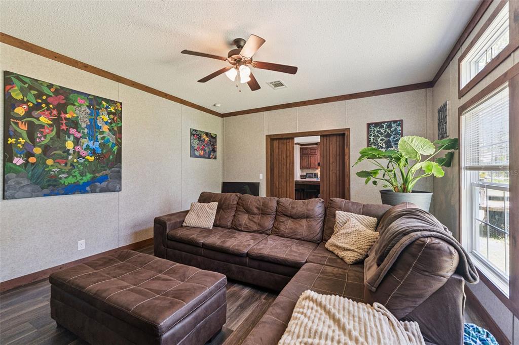 A living room features a brown sectional sofa, a wood-paneled fireplace wall, and a ceiling fan — 9740 EBERT AVENUE, HASTINGS, FL