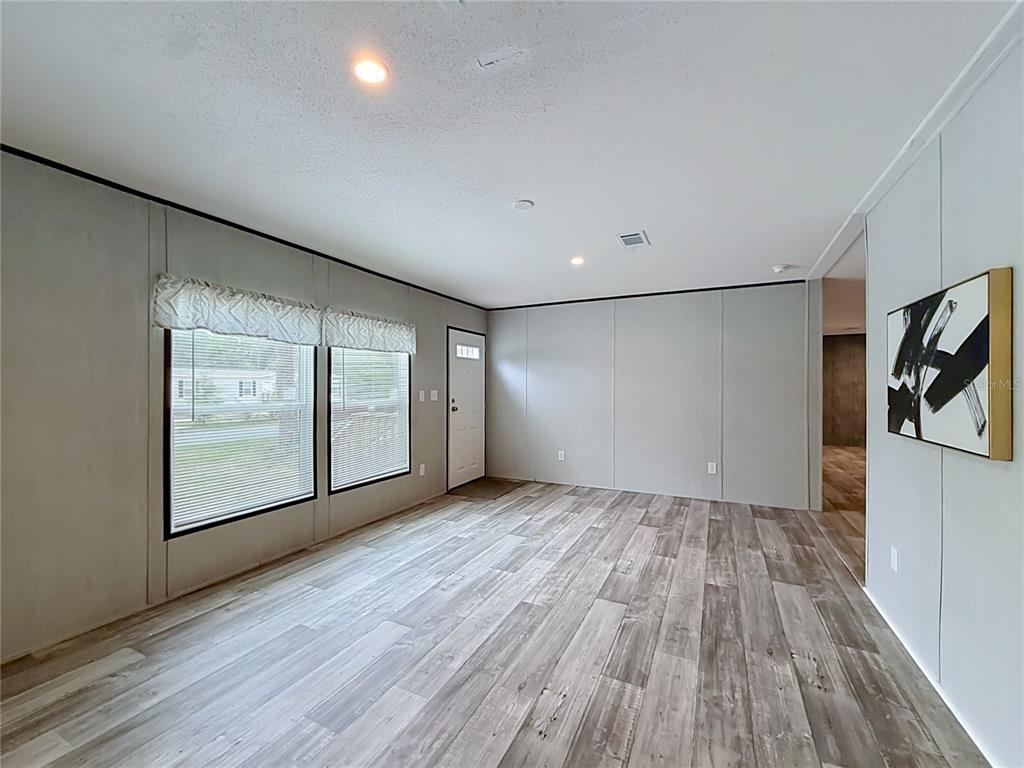 A living room features light gray walls, wood-look flooring, two windows, and a front door — 10055 W OHIO DRIVE, CRYSTAL RIVER, FL