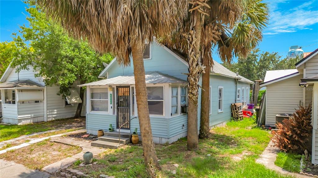 A light blue cottage with a metal roof and a front porch sits between two houses — 1417 11TH STREET, ST CLOUD, FL