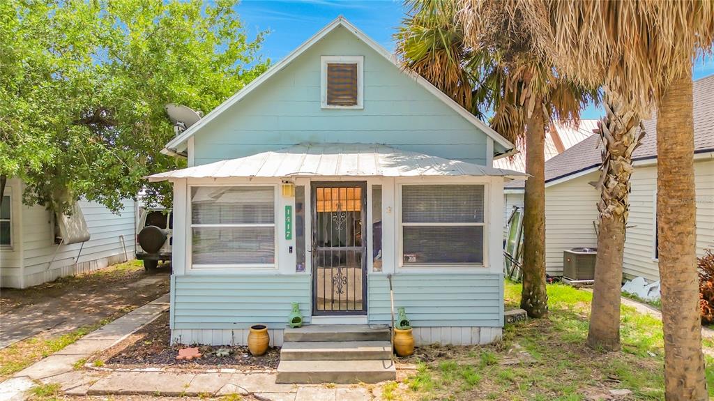 A light blue, single-story house with a metal roof and a screened-in front porch — 1417 11TH STREET, ST CLOUD, FL
