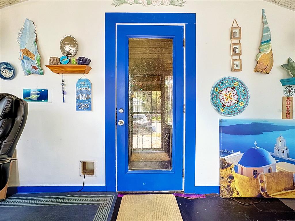 A bright blue door is centered on a white wall decorated with coastal-themed art — 1417 11TH STREET, ST CLOUD, FL