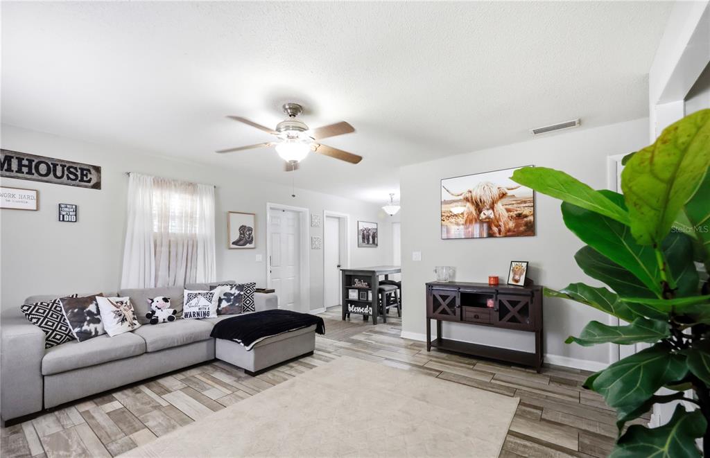 A living room features a gray sectional sofa, wood-look tile flooring, and a dining area — 786 E WARREN AVENUE, LONGWOOD, FL