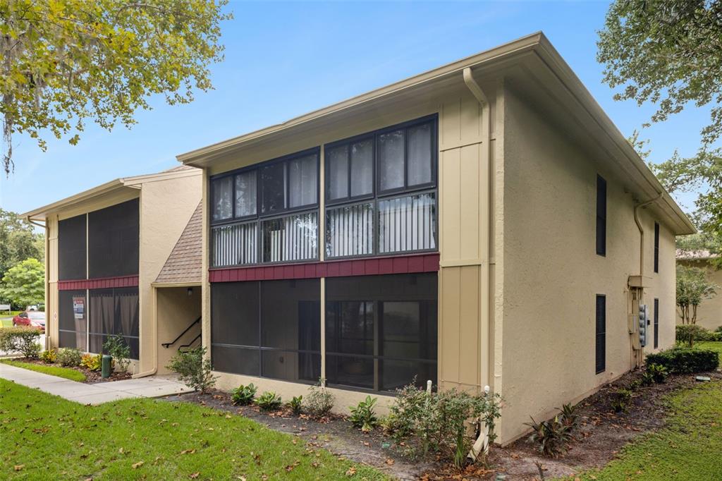 A two-story tan apartment building features screened-in porches on both levels and a shingled roof — 220 MOREE LOOP UNIT 1, WINTER SPRINGS, FL