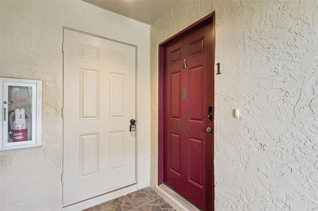 A white door and a red door labeled number one are set in a textured wall — 220 MOREE LOOP UNIT 1, WINTER SPRINGS, FL