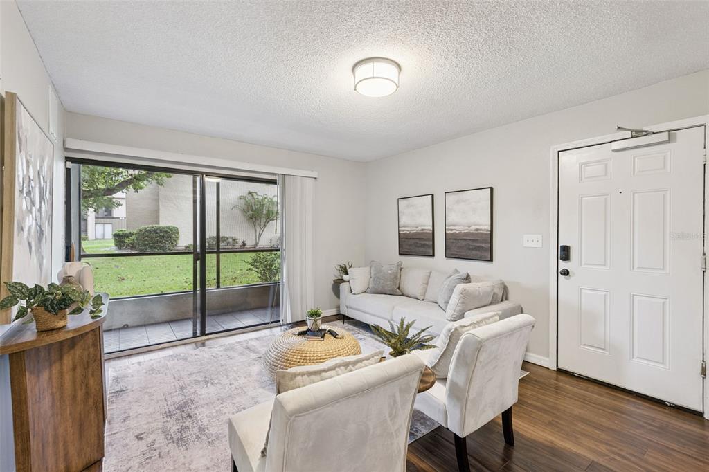 A living room features a white sofa, two armchairs, a rug, and a sliding glass door — 220 MOREE LOOP UNIT 1, WINTER SPRINGS, FL