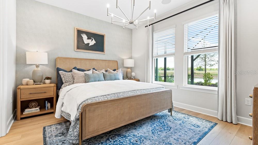 A bedroom features a cane bed, blue patterned rug, and large windows with outdoor views — 26084 ARBOR CIRCLE, PUNTA GORDA, FL