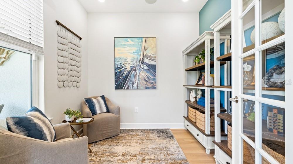 A home office features two armchairs, a sailboat painting, and white shelving against a blue wall — 26084 ARBOR CIRCLE, PUNTA GORDA, FL