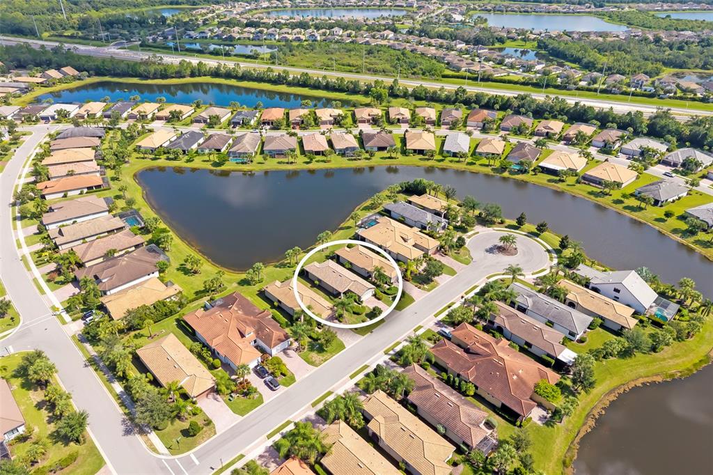 An aerial view shows a suburban neighborhood with a circled duplex home near a lake — 6726 HAVERHILL COURT, BRADENTON, FL