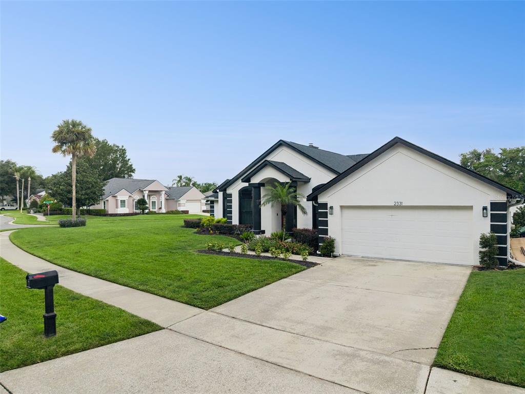 A single-story white house with a dark roof sits on a corner lot with grass — 2331 RIDGESIDE ROAD, APOPKA, FL