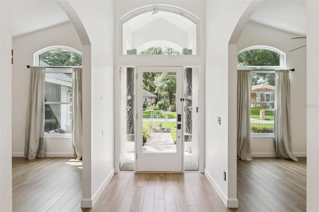 A living room features a vaulted ceiling, a ceiling fan, and a large arched window — 2331 RIDGESIDE ROAD, APOPKA, FL