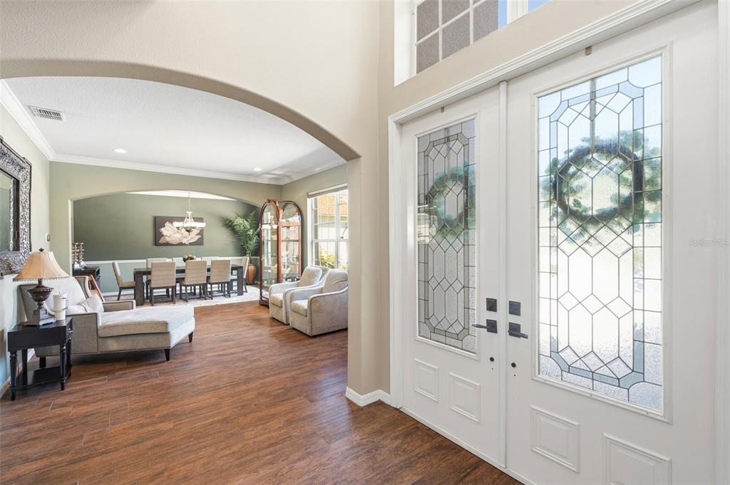 An entryway with double glass-paneled doors leads into a dining room with arched openings — 3449 LOGGERHEAD WAY, WESLEY CHAPEL, FL