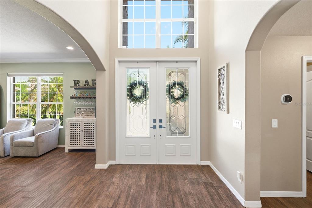 A bright foyer features double front doors, a high ceiling, and wood-look flooring — 3449 LOGGERHEAD WAY, WESLEY CHAPEL, FL