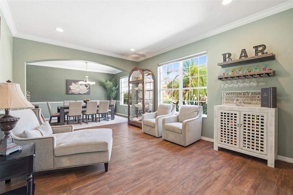 A living room with a dining area, wood-look floors, a bar cabinet, and two armchairs — 3449 LOGGERHEAD WAY, WESLEY CHAPEL, FL
