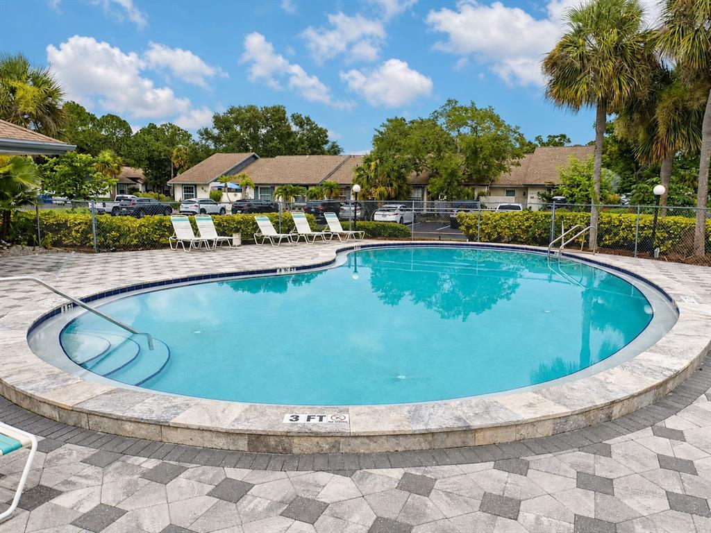 A kitchen features wood-grain cabinets, white appliances, and a large window with blinds — 3962 LA COSTA LANE, LARGO, FL