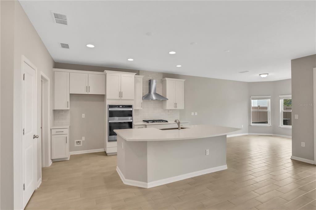 A kitchen with white cabinets, a large island, stainless steel appliances, and light-colored tile flooring — 3157 GADWALL RUN, ORANGE PARK, FL