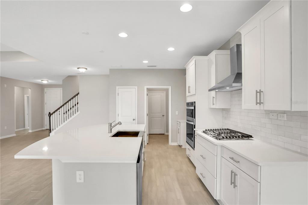 A modern kitchen features white cabinets, quartz countertops, a gas cooktop, and a center island — 3157 GADWALL RUN, ORANGE PARK, FL