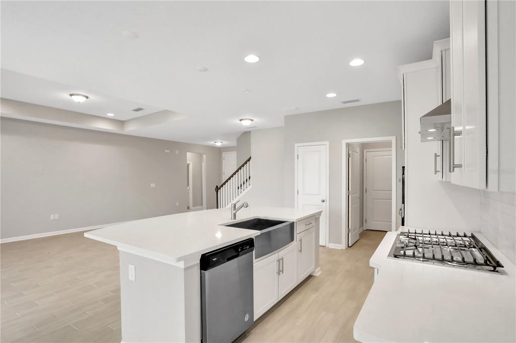 A modern kitchen features white cabinetry, a large island with a farmhouse sink, and light flooring — 3157 GADWALL RUN, ORANGE PARK, FL