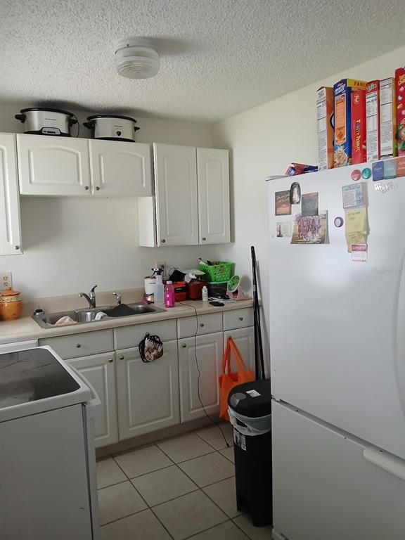 A kitchen with white cabinets, a double sink, a white refrigerator, and tiled flooring — 905 BEVERLY AVENUE, LARGO, FL