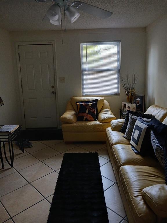 A living room features a tan leather sofa and armchair, tile flooring, and a ceiling fan — 905 BEVERLY AVENUE, LARGO, FL