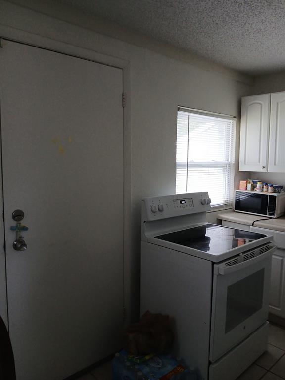 A kitchen features a white electric stove, a microwave, white cabinets, and a side door — 905 BEVERLY AVENUE, LARGO, FL