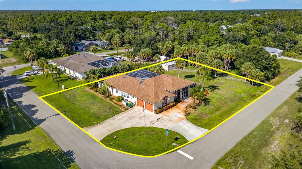 An aerial view shows a single-story house with a brown roof and pool enclosure on a corner lot — 17368 NORSEMAN AVENUE, PORT CHARLOTTE, FL