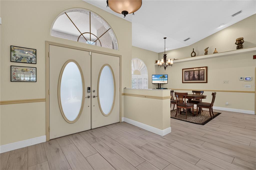 An entryway with double doors and a dining area featuring a chandelier and tile floors — 17368 NORSEMAN AVENUE, PORT CHARLOTTE, FL