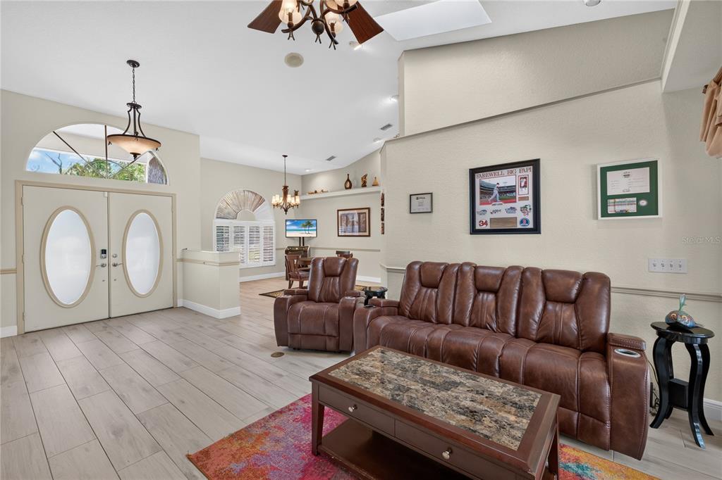 A living room features light wood-look tile flooring, a brown leather sofa, and a coffee table — 17368 NORSEMAN AVENUE, PORT CHARLOTTE, FL