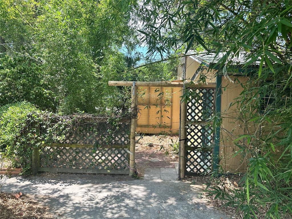 A wooden gate and lattice fence lead to a small backyard area beside a shed — 919 NW 23RD AVENUE, GAINESVILLE, FL