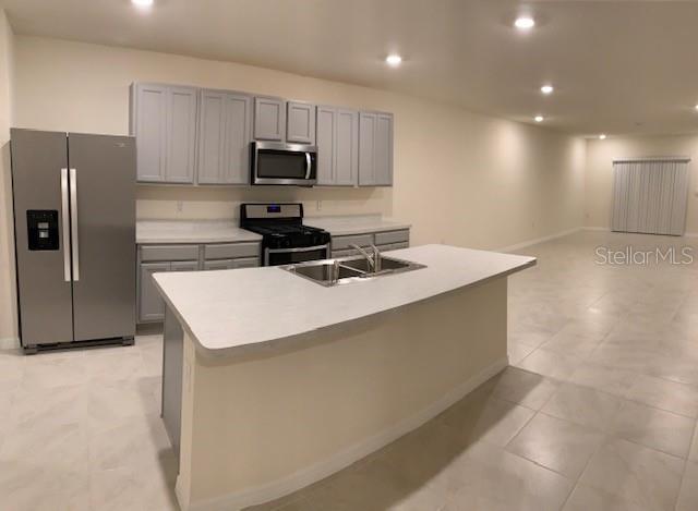 A kitchen with gray cabinets, stainless steel appliances, and a central island with a sink — 20007 ROYAL TERN COURT, LEESBURG, FL