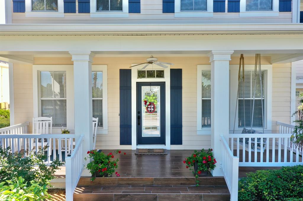 A front porch with a dark door, white columns, rocking chairs, and a hanging swing — 310 MANNS HARBOR DRIVE, APOLLO BEACH, FL