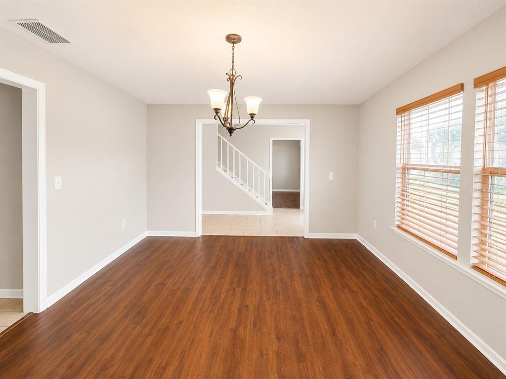 A dining room features a wooden table, six upholstered chairs, a chandelier, and a sideboard — 4104 QUAIL NEST COURT, ST CLOUD, FL