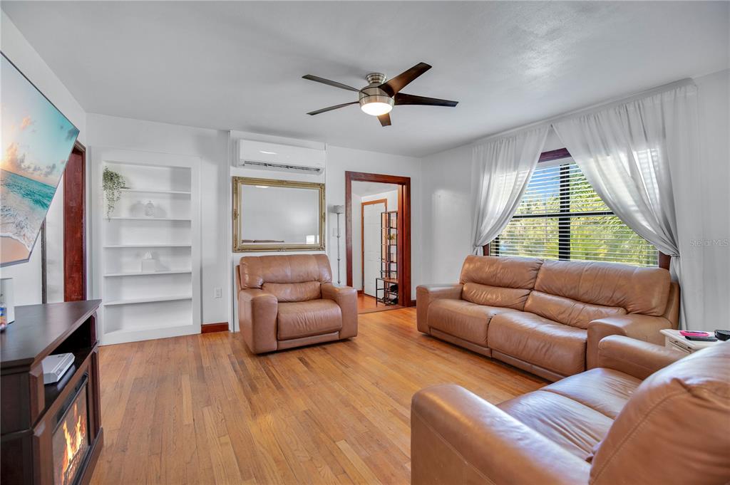 A living room features hardwood floors, leather furniture, a ceiling fan, and a fireplace — 11 ASTER DRIVE, DEBARY, FL