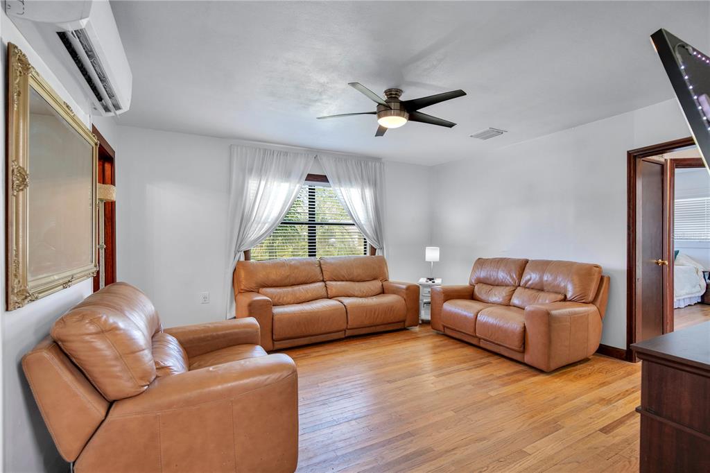 A living room features three tan leather sofas, hardwood floors, and a ceiling fan — 11 ASTER DRIVE, DEBARY, FL
