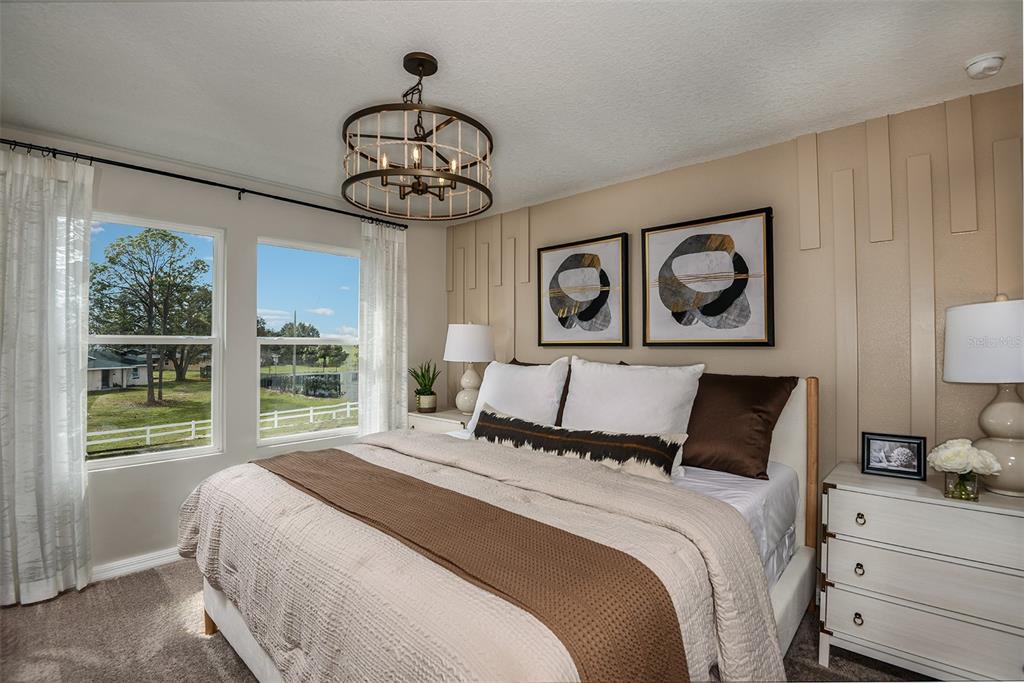 A bedroom features a bed with brown bedding, a wood-beaded chandelier, and a paneled accent wall — 4247 HILLOCK BOULEVARD, HAINES CITY, FL