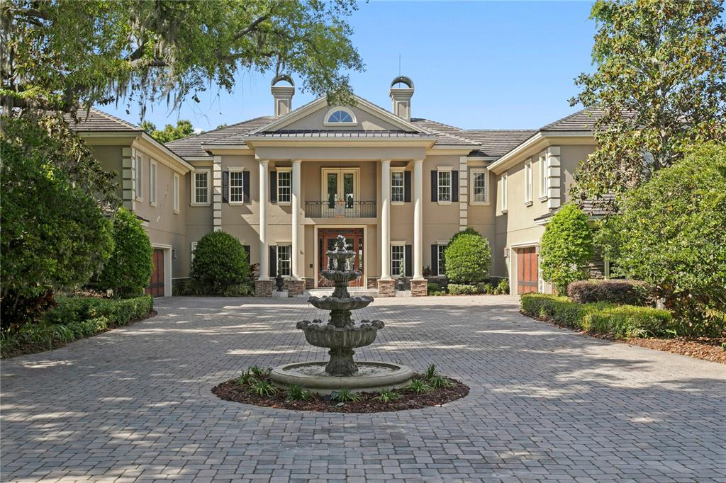 A large, two-story house with a columned entrance and a stone fountain in the driveway — 9205 POST ROAD, ODESSA, FL