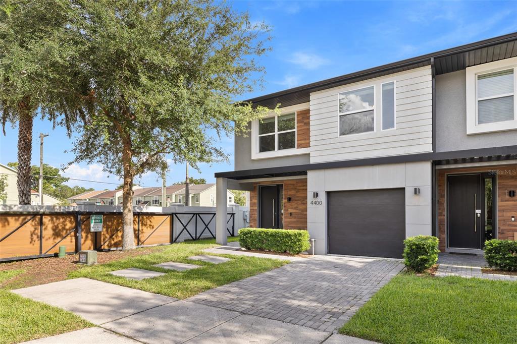 A modern two-story townhouse with a paved driveway, garage, and wood-accented exterior facade — 4400 LE REVE COURT, KISSIMMEE, FL