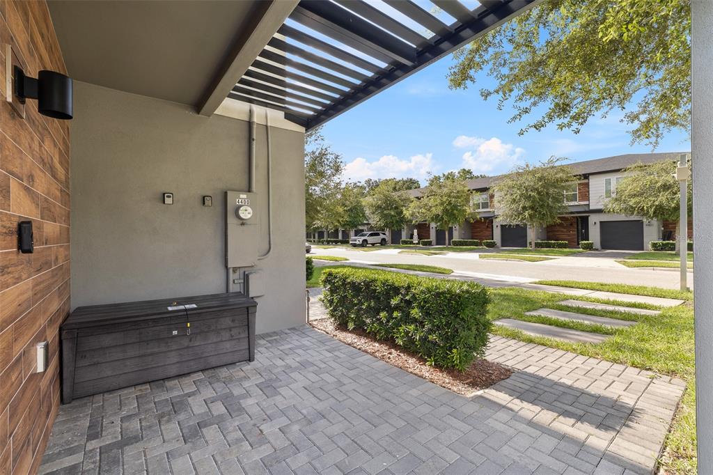 A paved entryway features a dark storage chest, a utility meter, and a slatted roof overhang — 4400 LE REVE COURT, KISSIMMEE, FL