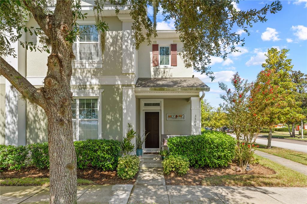 A two-story house exterior features a front porch, a dark door, and landscaped bushes — 3500 SEBASTIAN BRIDGE LANE, ST CLOUD, FL