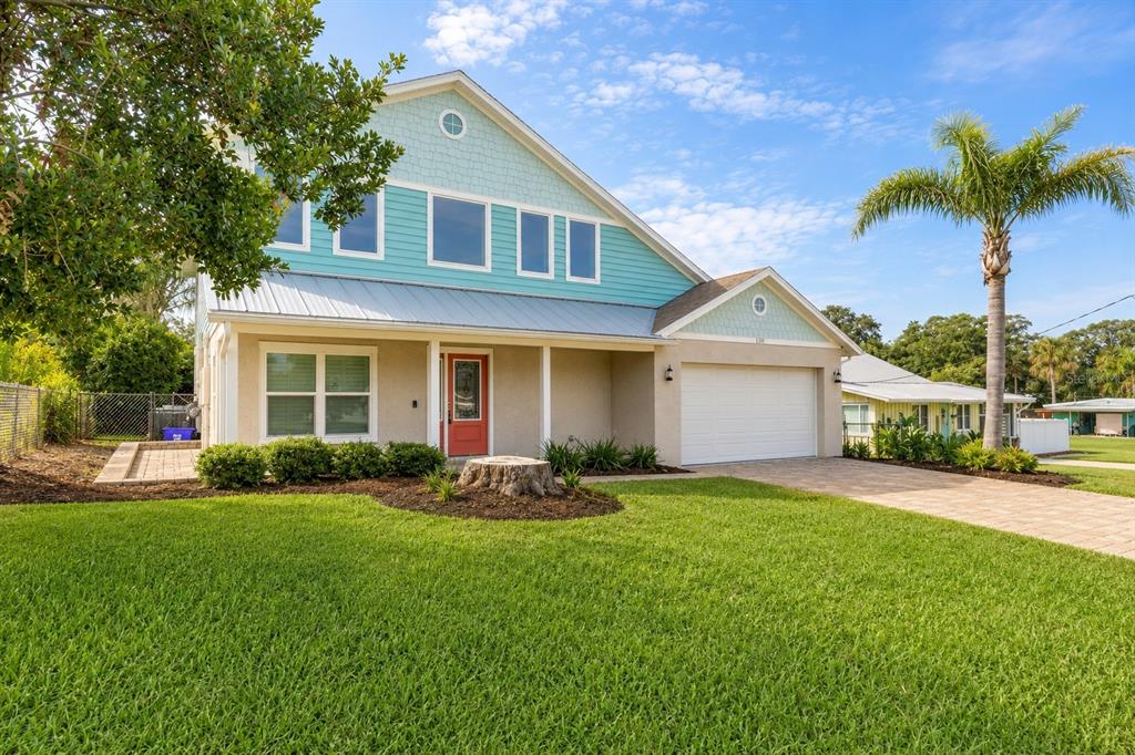 A two-story house with light blue siding, a red front door, and a paved driveway — 130 HERNANDEZ AVENUE, ORMOND BEACH, FL