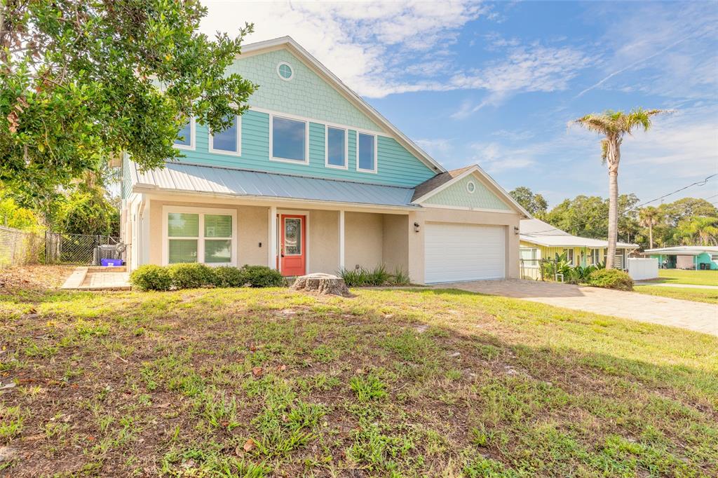 A two-story house with light blue siding, a red front door, and a two-car garage — 130 HERNANDEZ AVENUE, ORMOND BEACH, FL
