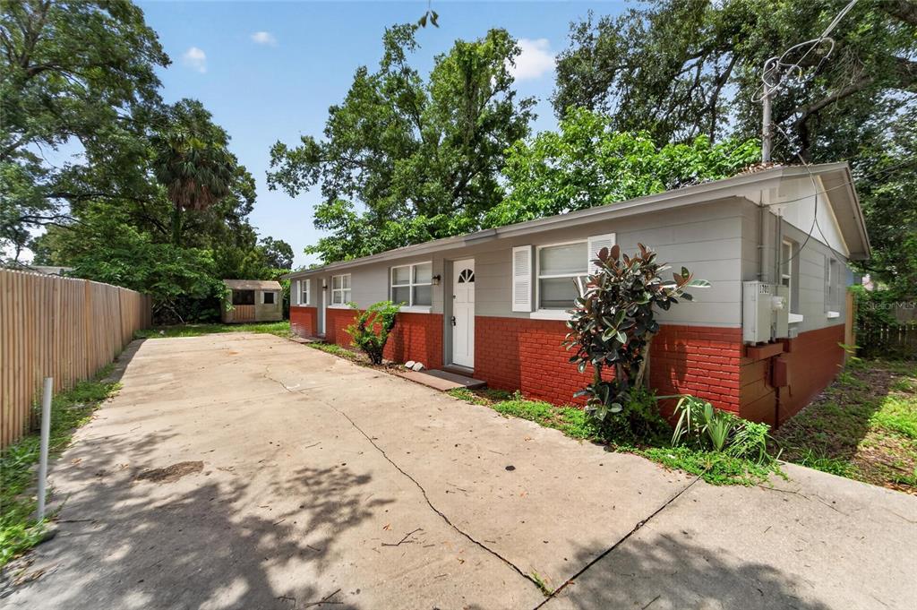 A single-story house with a red brick base, gray siding, and a concrete driveway — 1703 E IDELL STREET, TAMPA, FL