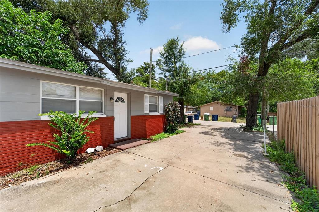 A single-story house with red brick and gray siding features a concrete driveway and trees — 1703 E IDELL STREET, TAMPA, FL
