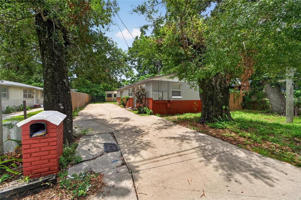 A concrete driveway leads to a single-story house with gray and red exterior walls — 1703 E IDELL STREET, TAMPA, FL