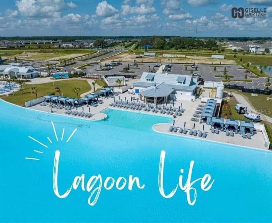An aerial view shows a large swimming lagoon with poolside cabanas and a clubhouse building — 10747 LAXER CAY LOOP, SAN ANTONIO, FL