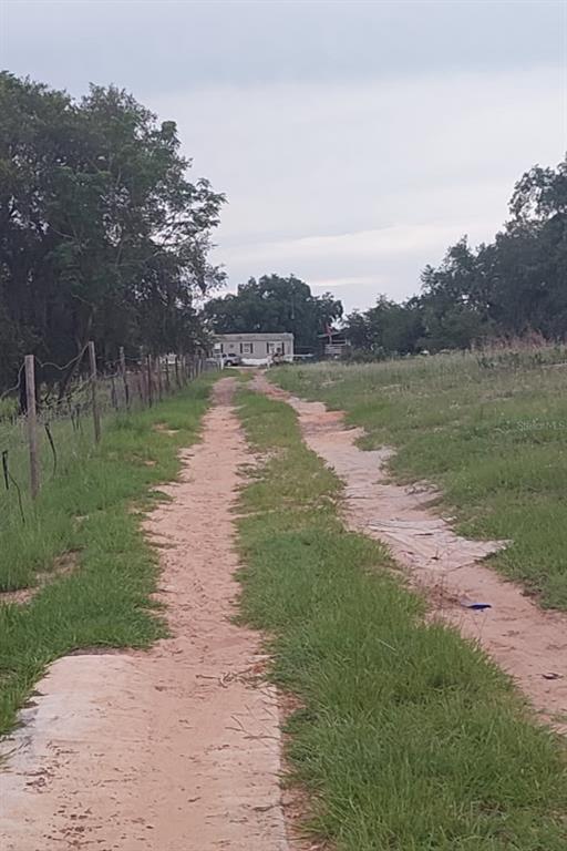 A dirt driveway leads toward a single-story mobile home surrounded by trees and grass — 562 LIBBY ROAD, BABSON PARK, FL