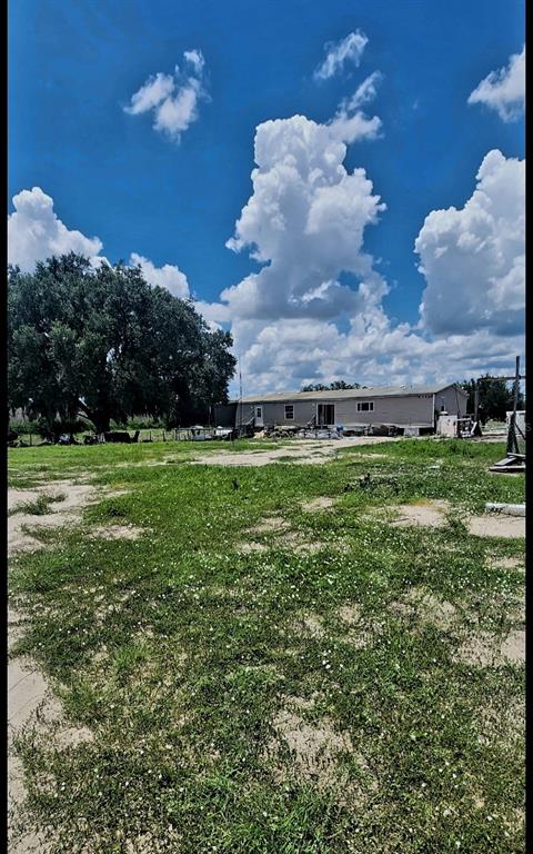 A single-story manufactured home sits on a large, grassy lot under a cloudy blue sky — 562 LIBBY ROAD, BABSON PARK, FL