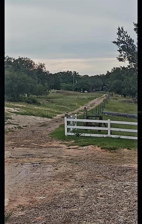 A dirt path leads through a grassy field past a white fence and trees — 562 LIBBY ROAD, BABSON PARK, FL