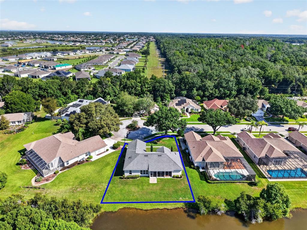 An aerial view shows a single-story house with a blue outline on a waterfront lot — 6022 FALCONBRIDGE PLACE, MOUNT DORA, FL