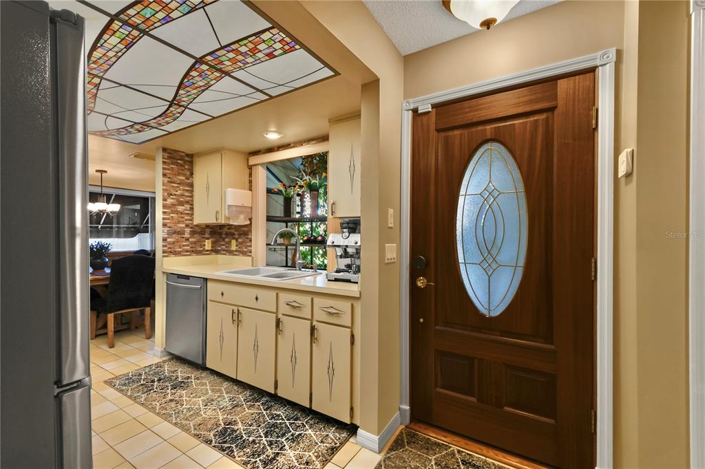 A kitchen area with light cabinets and a stained-glass ceiling panel next to a front door — 3884 VILLA ROSE LANE, ORLANDO, FL